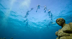 Membres de Greenpeace protesten sota l'aigua contra el canvi climàtic en un museu submarí de Cancún. (Foto: EFE)