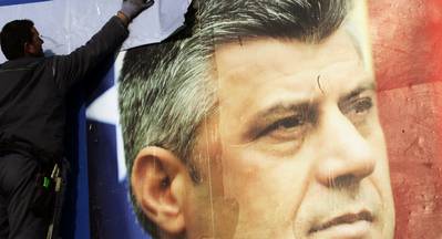 Un operari retira un cartell electoral amb la cara del primer ministre Thaçi.