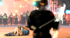 Una parella es fa un petó al carrer de Vancouver amb un policia en primer pla. (Foto: "The Guardian")
