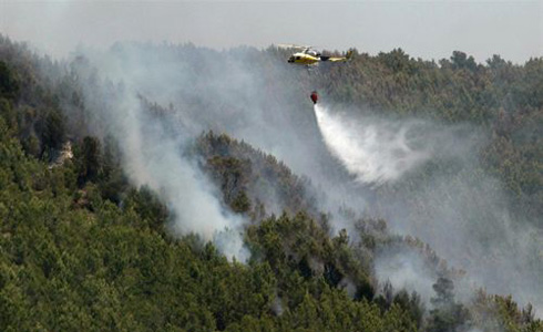 Un helicoptero llança aigua al foc