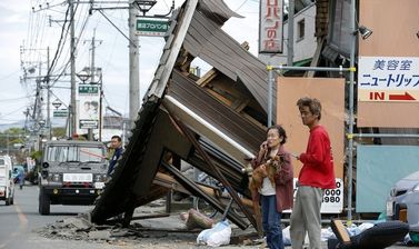 Una dona parlar per telèfon al costat d'un edifici destruït durant el segon terratrèmol a la prefectura japonesa de Kumamoto /