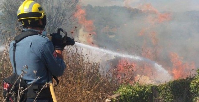 Un bomber, apagant el foc a la zona de matolls