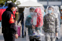 Unos ciudadanos caminan con máscaras y cubiertos de bolsas de plástico en Shanghái.