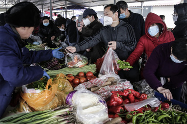 Gente comprando con mascarillas en un mercado de Wuhan a finales de enero.