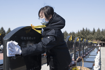 Una mujer limpia una lápida en uno de los cementerios de Harbin (China)
