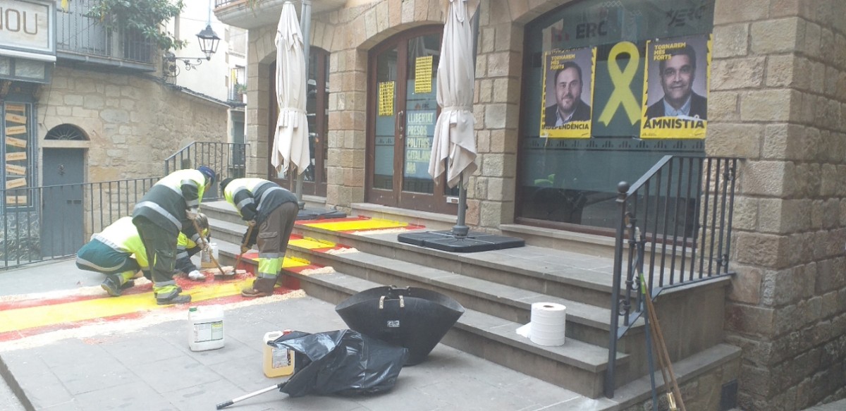 Treballadors del servei de neteja procedien a retirar la pintura del paviment