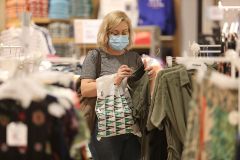 Una mujer con mascarilla compra en un centro comercial.