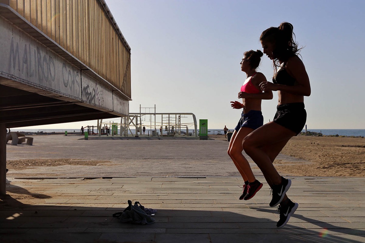 Dues noies fan exercici a la Barceloneta a primera hora.