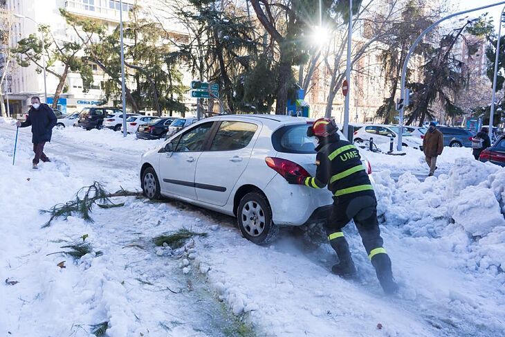 Un militar de la UME empuja un coche atascado por la nieve en una calle de Madrid.