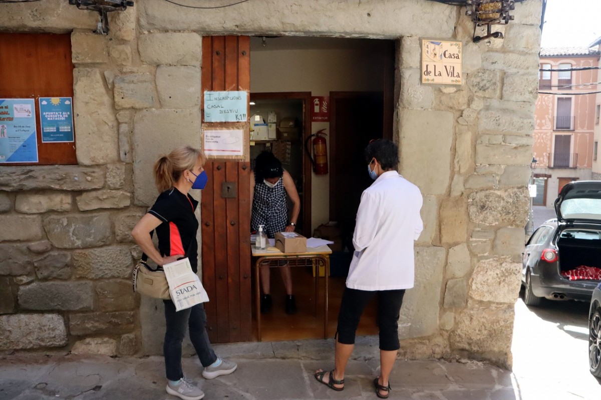 Dues persones esperen a l'exterior de l'oficina de Correus de Sant Llorenç de Morunys